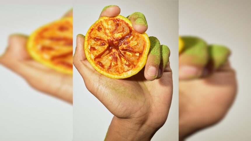 A hand dusted with matcha holding half a yuzu covered in gochujang. Food styled by Maggie Ruggiero, flavours