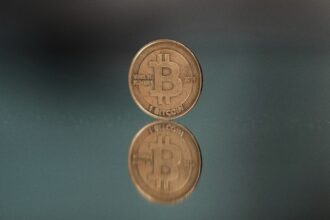 A one bitcoin token reflects as it is placed on a mirror in Prague