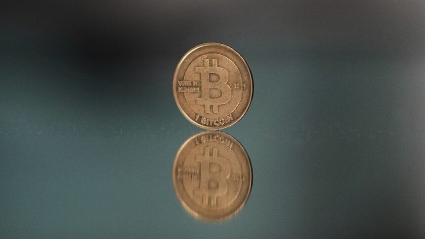 A one bitcoin token reflects as it is placed on a mirror in Prague