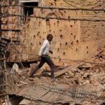 A man walks amid debris on the roof of a damaged house, following Pakistan's shelling in Jammu region on Saturday
