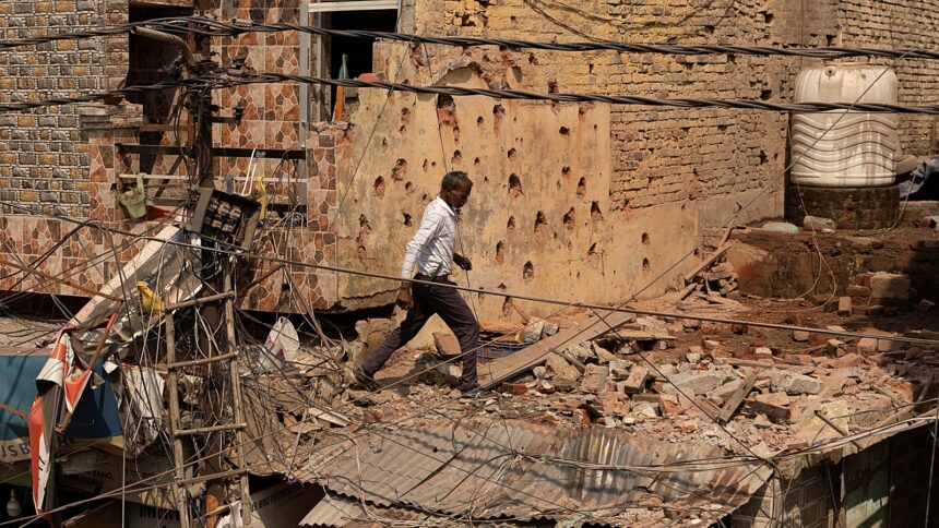 A man walks amid debris on the roof of a damaged house, following Pakistan's shelling in Jammu region on Saturday