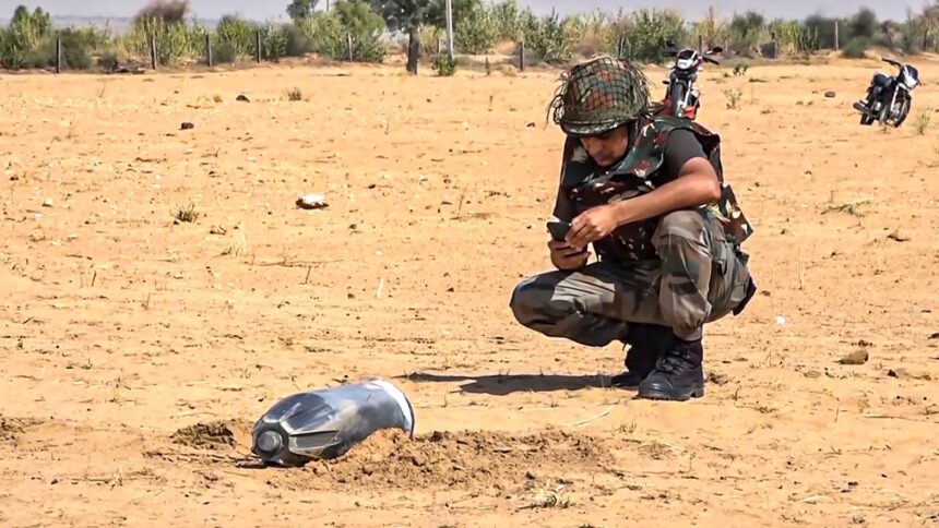 A security personnel inspects the debris of an unidentified projectile which landed amid the military conflict between India and Pakistan in Jaisalmer. (PTI)