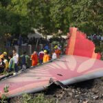 People stand around the debris of the Air India airplane after it crashed in Ahmedabad on Thursday