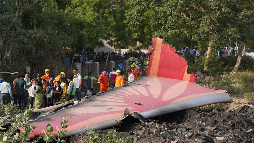 People stand around the debris of the Air India airplane after it crashed in Ahmedabad on Thursday