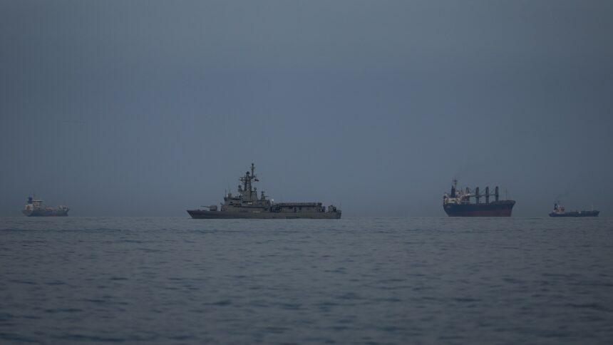 A UAE navy vessel patrols next to cargo ships and oil tankers in the Strait of Hormuz as seen from Khor Fakkan, United Arab Emirates.