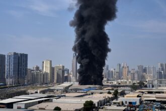 A black plume of smoke rises from a warehouse at the industrial area of Sharjah City in the United Arab Emirates following reports of Iranian strikes in Dubai. (AP Photo)