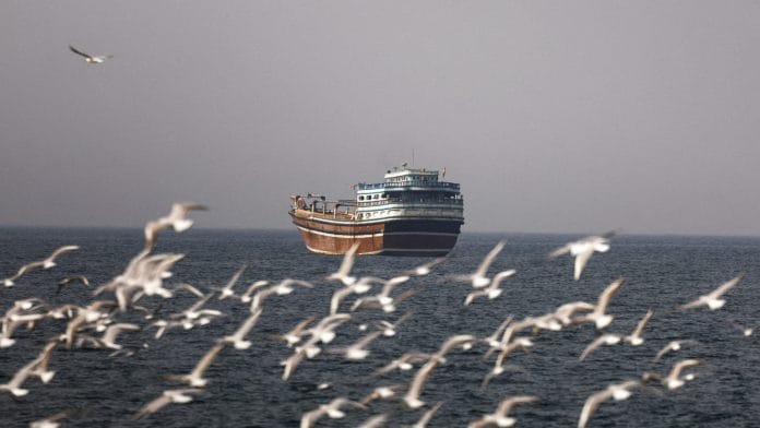 FILE PHOTO: Birds fly near a boat in the Strait of Hormuz amid the U.S.-Israeli conflict with Iran, as seen from Musandam, Oman, March 2, 2026. | REUTERS/Amr Alfiky/File Photo