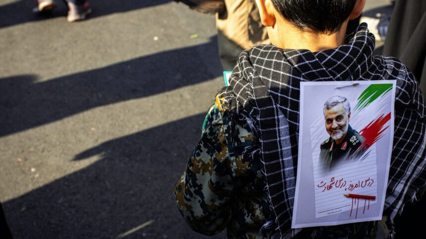 AN Iranian child with a poster of slain military leader Qassem Soleimani pinned to his back during the 2020 Iran-US conflict (Unsplash@hoseinchaharbaghi).