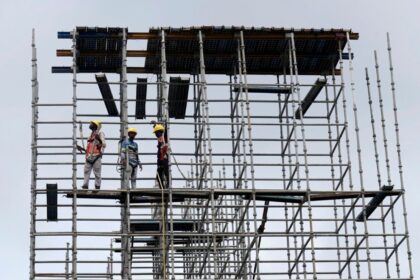 Migrant construction workers on a scaffold in Kerala, as large-scale return migration for elections in West Bengal and Assam disrupts key labour-dependent industries.