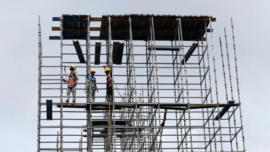 Migrant construction workers on a scaffold in Kerala, as large-scale return migration for elections in West Bengal and Assam disrupts key labour-dependent industries.