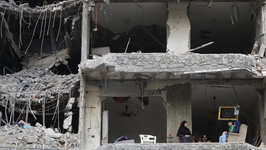 The wife and children of Fadi Al Zein, who lost both his homes in Israeli strikes in his village of Khiam and in Dahiyeh, sit on the balcony of their heavily damaged apartment building in Beirut's southern suburbs