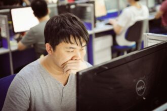 Man yawning while working at computer in office.