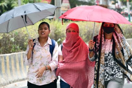 Women cover their faces with scarves and shield themselves from the heat with umbrellas on a hot summer day