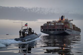 An IRGC speedboat approaches the cargo ship Epaminondas during what state media described as the seizure of one of two vessels accused of violations in the Strait of Hormuz. (AP Photo)