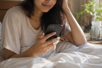 Woman using her phone right after waking up