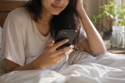 Woman using her phone right after waking up