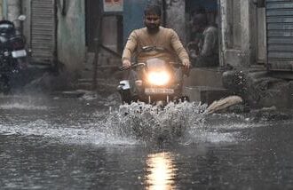 Commuters walk through a waterlogged area after Heavy Rain.   (Photo by Ishant Chauhan/Hindustan Times)