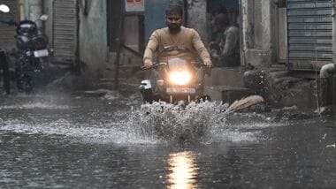 Commuters walk through a waterlogged area after Heavy Rain.   (Photo by Ishant Chauhan/Hindustan Times)