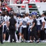 Members of the Utah State Aggies stand around the ambulance as teammate Harrison Taggart #0 is loaded in after an injury during the first half of their game against the Utah Utes at Rice-Eccles Stadium.