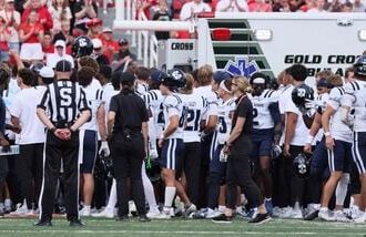 Members of the Utah State Aggies stand around the ambulance as teammate Harrison Taggart #0 is loaded in after an injury during the first half of their game against the Utah Utes at Rice-Eccles Stadium.