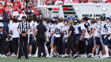 Members of the Utah State Aggies stand around the ambulance as teammate Harrison Taggart #0 is loaded in after an injury during the first half of their game against the Utah Utes at Rice-Eccles Stadium.