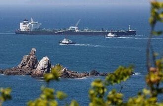 Tugboats guide a crude-oil tanker after passing through the Strait of Hormuz.