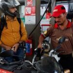 A man watches the litres and rupee amount displayed at the pump as he refuels his vehicle at a petrol station, as fuel prices rise amid the US-Iran conflict