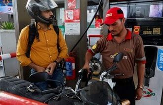 A man watches the litres and rupee amount displayed at the pump as he refuels his vehicle at a petrol station, as fuel prices rise amid the US-Iran conflict