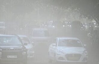 Commuters make their way through a haze-covered and dusty stretch of road as air pollution levels rise in New Delhi (Photo by Sanchit Khanna/ Hindustan Times)
