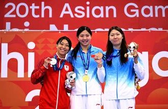 Silver medallist Japan's Satomi Suzuki (L), gold medallist China's Tang Qianting (C) and bronze medallist China's Yang Chang (R) celebrate on the podium of the women's 50m breaststroke swimming event during the 2026 Asian Games at the Tokyo Aquatics Centre in Tokyo.