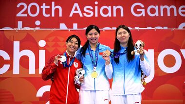 Silver medallist Japan's Satomi Suzuki (L), gold medallist China's Tang Qianting (C) and bronze medallist China's Yang Chang (R) celebrate on the podium of the women's 50m breaststroke swimming event during the 2026 Asian Games at the Tokyo Aquatics Centre in Tokyo.