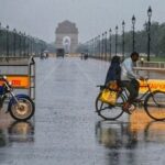 Commuters make their way through a rain-slicked road following heavy rainfall near India Gate, in New Delhi.
