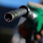 A man holds a fuel nozzle at a petrol station