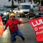 Supporters hold campaign flags depicting Brazilian President Luiz Inacio Lula da Silva, who is running for reelection, during a campaign event on a street in Brasilia, Brazil, Wednesday, Sept. 30, 2026. (AP Photo/Eraldo Peres)
