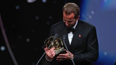 England and Bayern Munich forward Harry Kane looks at the Ballon d'Or trophy after winning it during a ceremony in London on Monday.