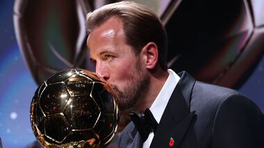 England and Bayern Munich forward Harry Kane kisses the trophy on stage after receiving the Ballon d'Or award for the best male footballer during the 2026 Ballon d'Or France Football award ceremony at the Palladium Theatre in London.