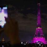 People use their smartphones to capture footage of the Eiffel Tower, illuminated in pink for Pink October, the annual worldwide campaign promoting breast cancer screening, in Paris
