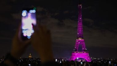 People use their smartphones to capture footage of the Eiffel Tower, illuminated in pink for Pink October, the annual worldwide campaign promoting breast cancer screening, in Paris