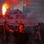 A protester holds a flare as students, teachers and civil servants take part in a rally to protest against the high cost of living, saying they face the same problems that sparked violent demonstrations in France at the weekend, in Athens on October 21, 2026. (Photo by Angelos TZORTZINIS / AFP)