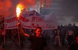 A protester holds a flare as students, teachers and civil servants take part in a rally to protest against the high cost of living, saying they face the same problems that sparked violent demonstrations in France at the weekend, in Athens on October 21, 2026. (Photo by Angelos TZORTZINIS / AFP)