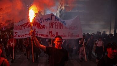 A protester holds a flare as students, teachers and civil servants take part in a rally to protest against the high cost of living, saying they face the same problems that sparked violent demonstrations in France at the weekend, in Athens on October 21, 2026. (Photo by Angelos TZORTZINIS / AFP)