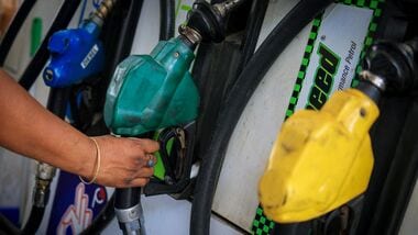 FILE PHOTO: A worker holds a nozzle to pump fuel in a vehicle at a petrol pump in New Delhi