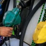 FILE PHOTO: A worker holds a nozzle to pump fuel in a vehicle at a petrol pump in New Delhi