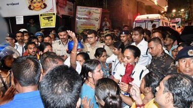People gather outside as police officers set up a barricade at the entrance to a worship venue for the Hindu festival of Durga Puja following a stampede, in Kolkata, India, Saturday, Oct. 17, 2026. (AP Photo)