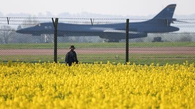 A person standing in a field of oilseed rape, views a U.S. Air Force B‑1B Lancer military aircraft parked at RAF Fairford airbase, after a two-week ceasefire in the Iran war was announced, in Fairford, Gloucestershire, Britain, April 8, 2026. REUTERS/Toby Melville