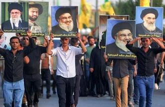 Supporters of Iran-aligned armed factions march with portraits of Iran's slain supreme leader Ali Khamenei, Lebanese Hezbollah movement's slain leader Hassan Nasrallah, and Iraq's supreme Shia Muslim cleric Ayatollah Ali Sistani, during a rally celebrating the withdrawal of forces of the US-led coalition against the Islamic State from Iraq, in Baghdad on September 30, 2026.(Photo by AHMAD AL-RUBAYE / AFP)
