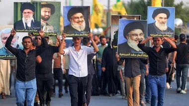 Supporters of Iran-aligned armed factions march with portraits of Iran's slain supreme leader Ali Khamenei, Lebanese Hezbollah movement's slain leader Hassan Nasrallah, and Iraq's supreme Shia Muslim cleric Ayatollah Ali Sistani, during a rally celebrating the withdrawal of forces of the US-led coalition against the Islamic State from Iraq, in Baghdad on September 30, 2026.(Photo by AHMAD AL-RUBAYE / AFP)