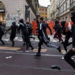 Protesters run along a street strewn with debris during a protest over the state of public services and the rising cost of living in Milan, Italy, October 18, 2026. REUTERS/Stringer