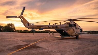 TOPSHOT - A general view of a Nigerian Air Force helicopter parked on the tarmac of the Maiduguri Air Force Baseb as the sun sets on August 2, 2026. Northeast Nigeria has been gripped by an Islamist extremist insurgency since 2009, first by Boko Haram, then its offshoot and rival, the Islamic State West Africa Province (ISWAP). The groups have since last year stepped up reported attacks on villages, police stations and workers such as loggers and fishermen, as well as military bases, killing several senior army officers. The upsurge in attacks prompted President Bola Tinubu to declare a nationwide state of emergency in 2025 (Photo by AFP)