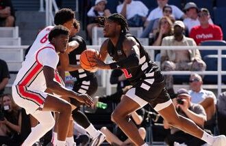 Jayden Hastings #22 of the Cincinnati Bearcats passes the ball while being guarded by Josh Ojianwuna #17 of the Ohio State Buckeyes in the first half of an exhibition game during the 2026 CareSource Invitational at the Lindner Family Tennis Center.